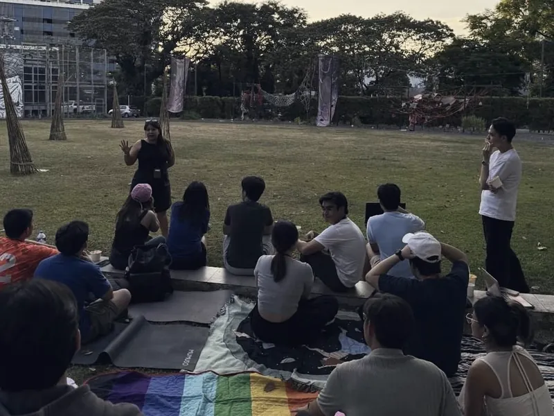 Members sitting in a circle on the grass at a fundraising event