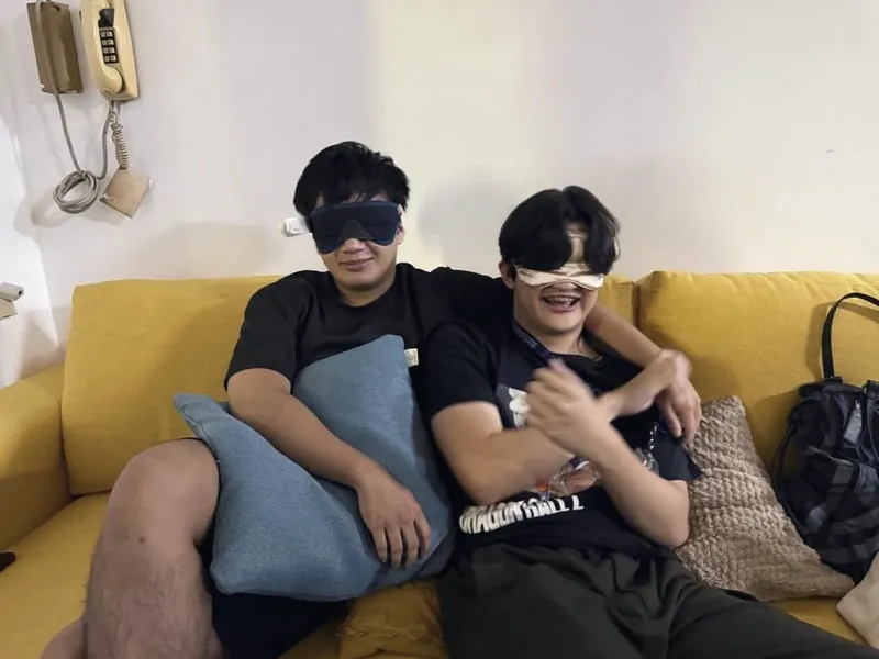 Two members in blindfolds laughing on a couch during a Venture Vibes icebreaker